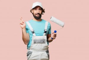 homeowner dressed in painting overalls looking worried and crossing their fingers