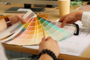 two people testing paint samples against a blueprint of a house