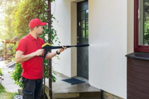 a professional painter power washing the outside of a house